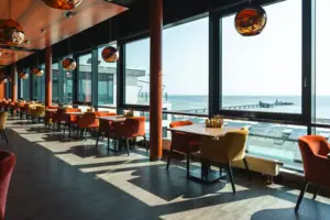 Restaurant Ein Raum mit Tischen und Stühlen, ein Fenster mit Blick auf den Ozean.