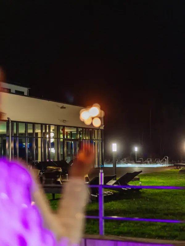 Een persoon staat voor het hotel met fonkelaars in de hand in de nacht.