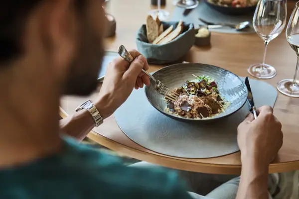 Eén persoon eet een maaltijd aan een tafel.