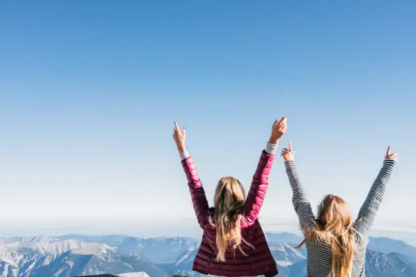 Zugspitze Twee vrouwen staan op een berg met hun armen omhoog.