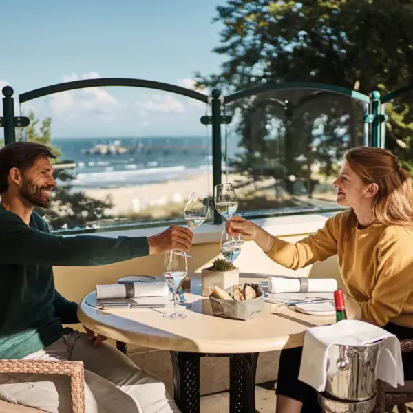 Een man en een vrouw zitten aan een tafel met glazen wijn.