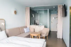 Tweepersoonskamer  Een kamer met een bank en een tafel.