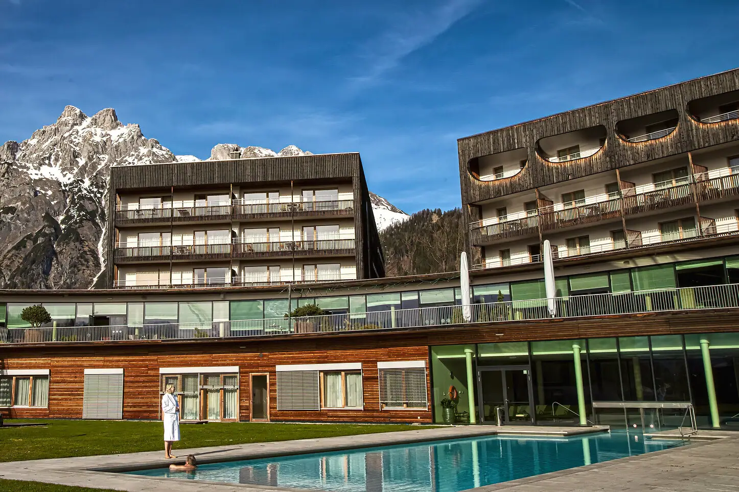 Persoon staat voor een buitenzwembad.