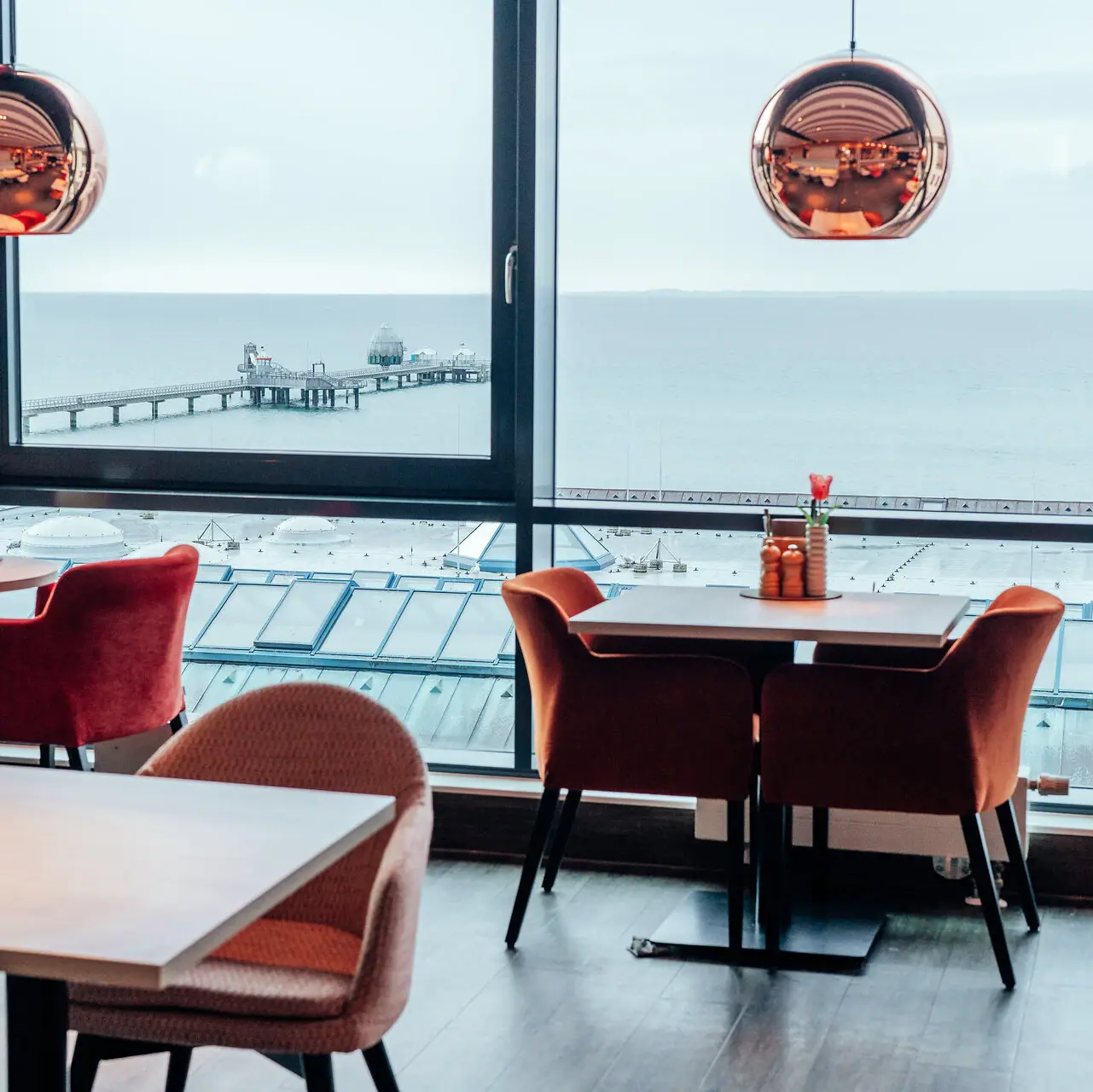 Een kamer met uitzicht op de oceaan en een pier.