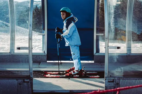 Kind op ski's buiten, met winterkleding aan.