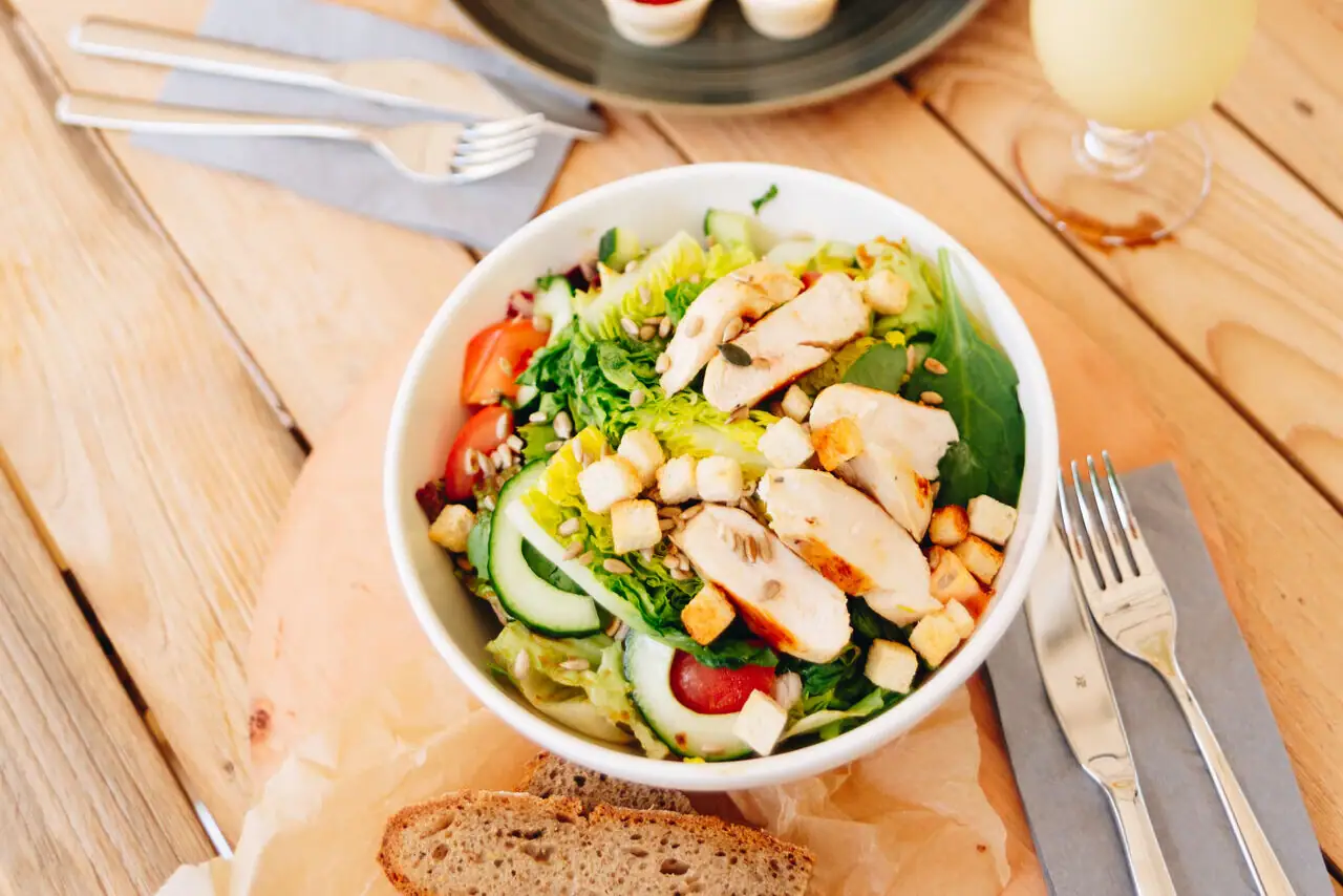 Salade met kip Een bord met eten en drinken op een tafel.