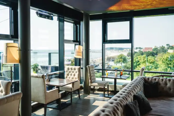 Een kamer met een groot raam, tafels en stoelen.