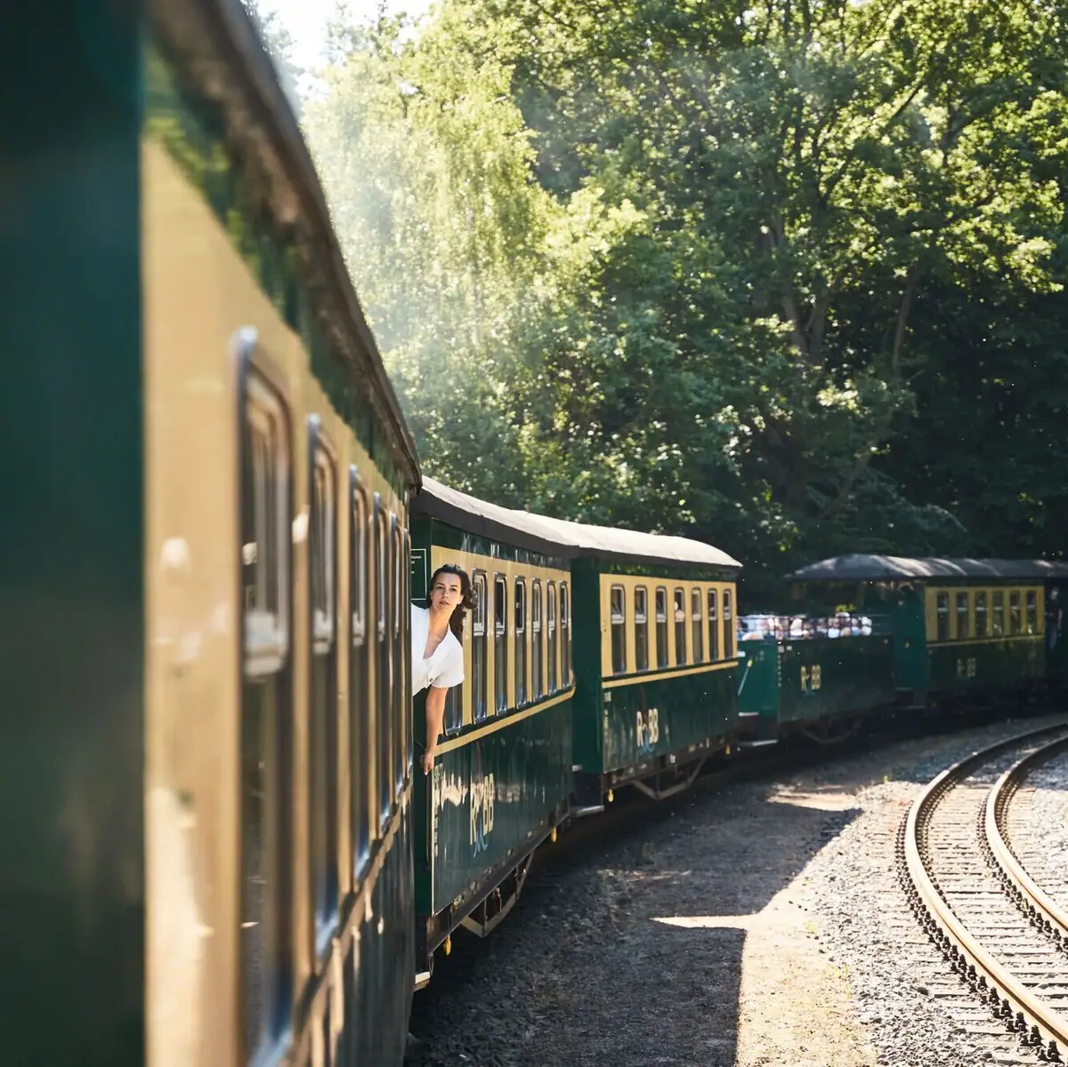 Een vrouw leunt uit het raam van een trein.