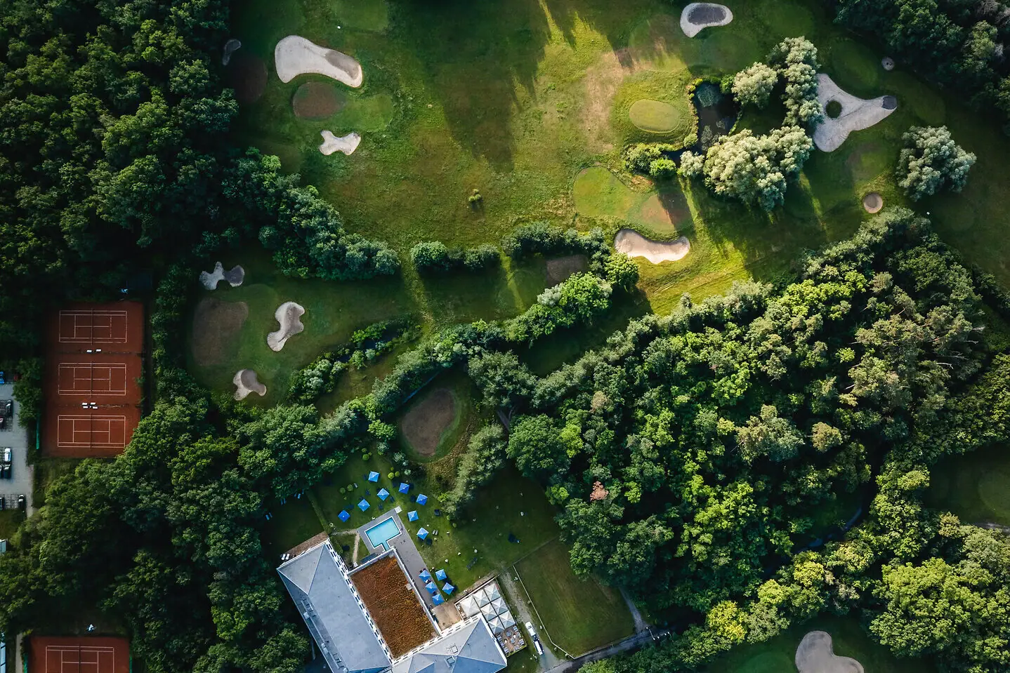 Luchtfoto van een golfbaan met bomen en een waterhindernis.