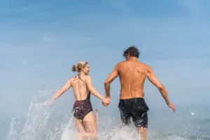 Ein Mann und eine Frau halten sich im Wasser an den Händen.