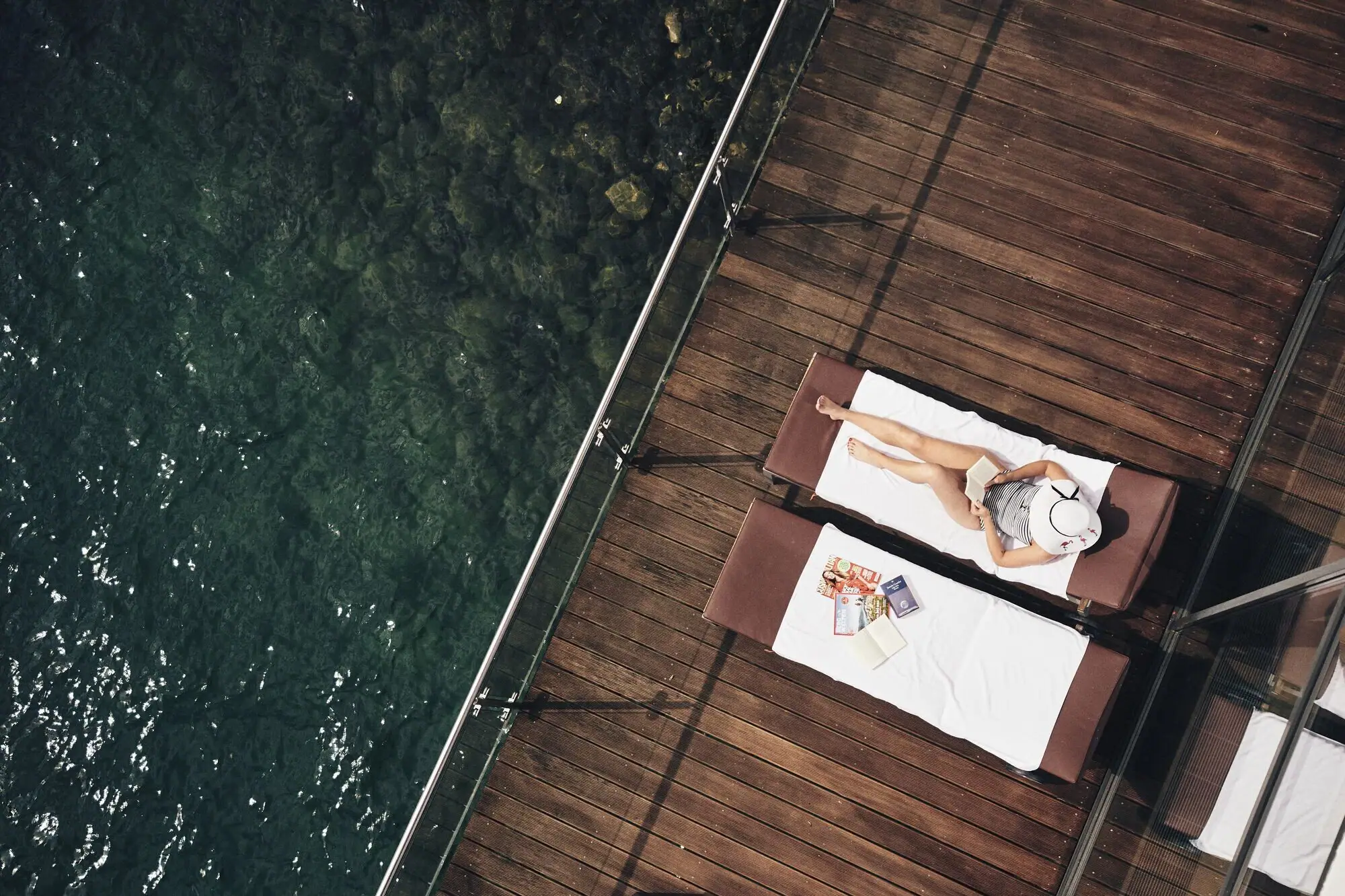 Een vrouw ligt op een ligstoel naast het water.