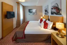 Kamers Achensee Een bed met kussens en een televisie in een hotelkamer aan de Achensee.