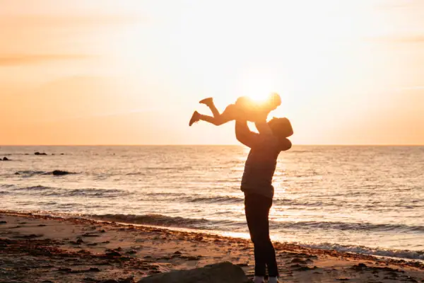 Een vrouw houdt een baby vast op het strand.