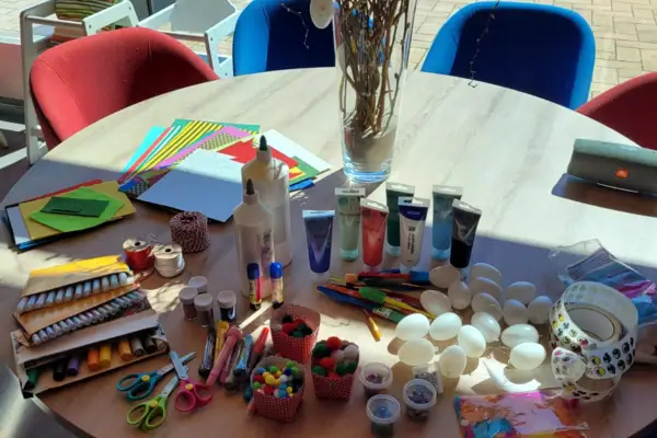 Een tafel met kunstbenodigdheden en een vaas met bloemen.