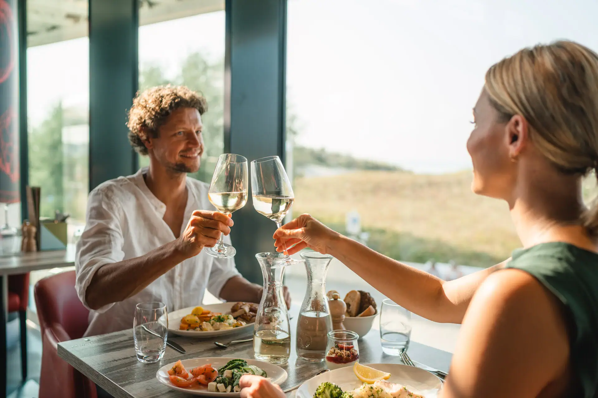 Diner Een man en een vrouw klinken glazen wijn aan een tafel.