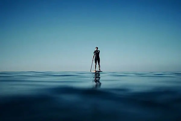 Een persoon op een paddleboard in de oceaan.
