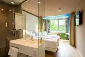 Een kamer met een glazen douche en twee bedden.