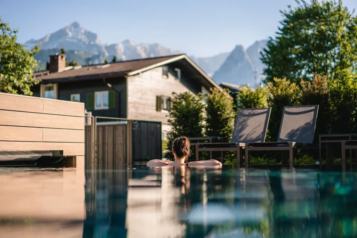 Buitenzwembad Een persoon in het zwembad met bomen op de achtergrond.