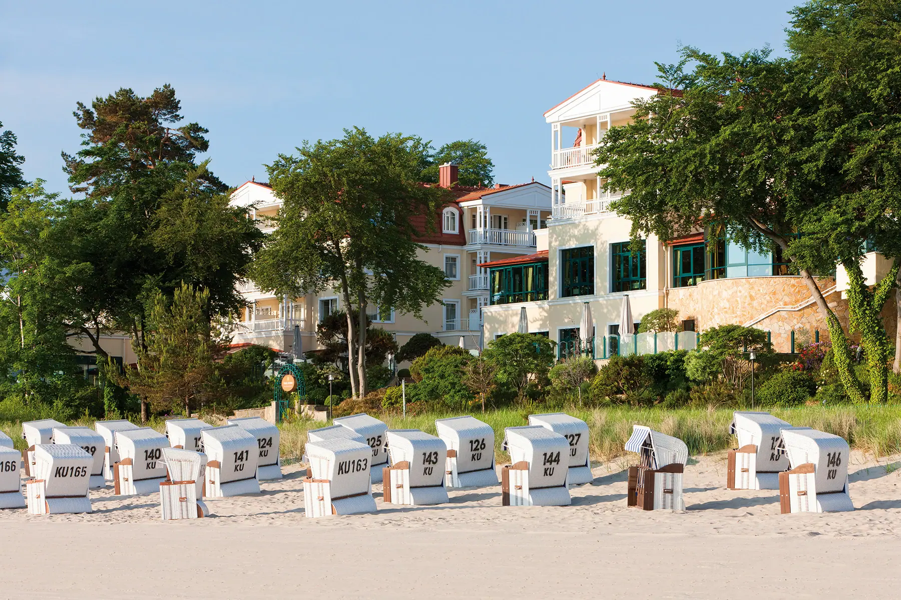 Een groep strandstoelen op het strand met het aja Strandhotel Bansin op de achtergrond.
