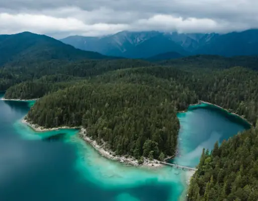 Eibsee vanuit vogelperspectief Een watermassa met bomen en bergen op de achtergrond.