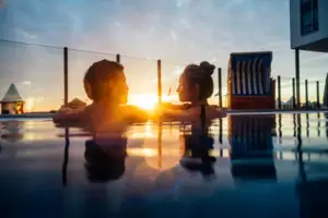 Ein Mann und eine Frau im Außenpool bei Sonnenuntergang.