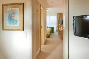 Junior suite met uitzicht op het meer en balkon Een gang met een televisie en een tafel.