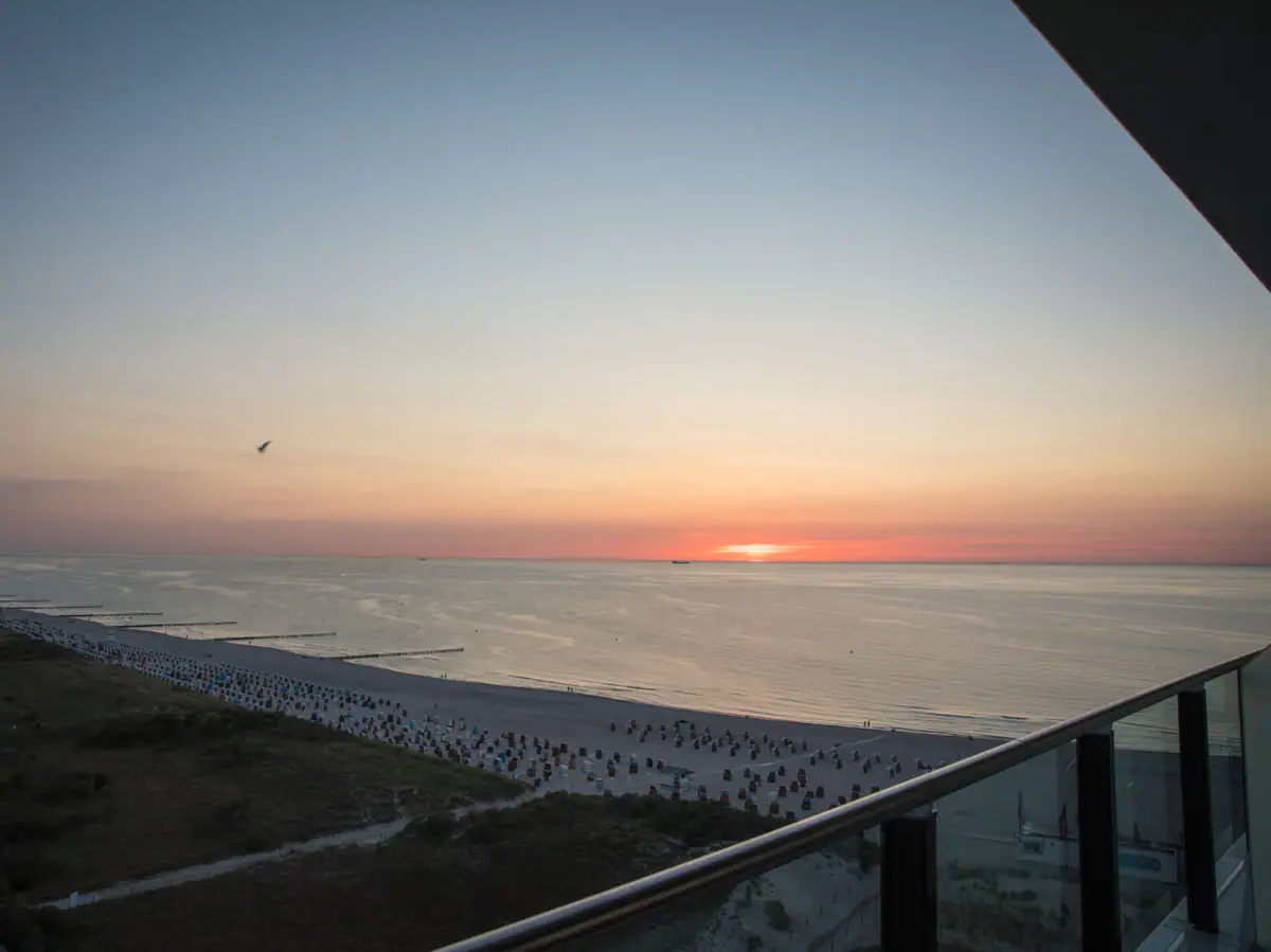 Vooruitzichten bij aja Warnemünde Uitzicht op het strand met water en zonsondergang op de achtergrond.