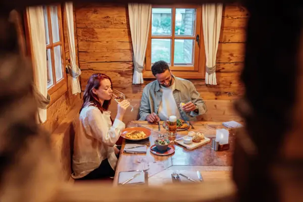 Een man en een vrouw zitten aan een tafel met eten en drinken.