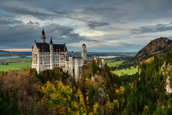 Kasteel Neuschwanstein op een heuvel met bergen op de achtergrond.