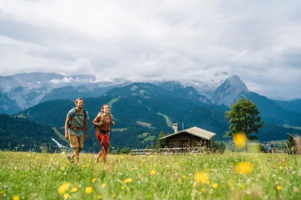 Een man en een vrouw maken in de zomer een wandeling in Garmisch-Partenkirchen, met de bergen op de achtergrond.